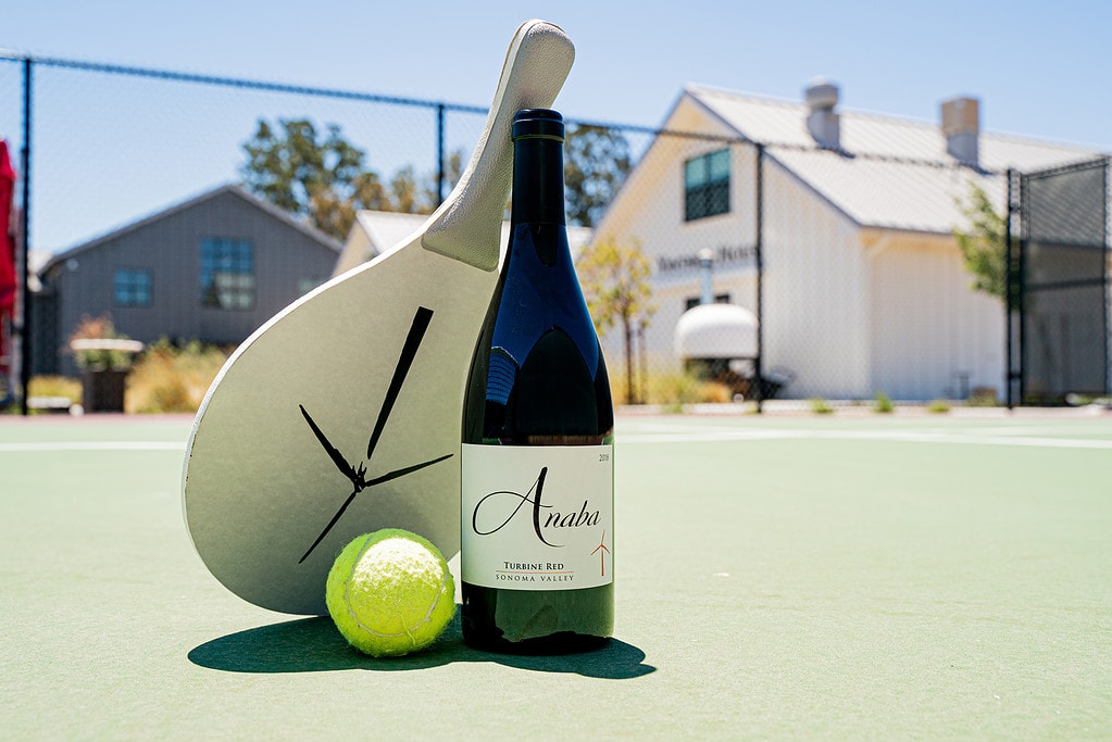 A paddle tennis ball, paddle, and a bottle of Turbine Red on our estate paddle tennis court.