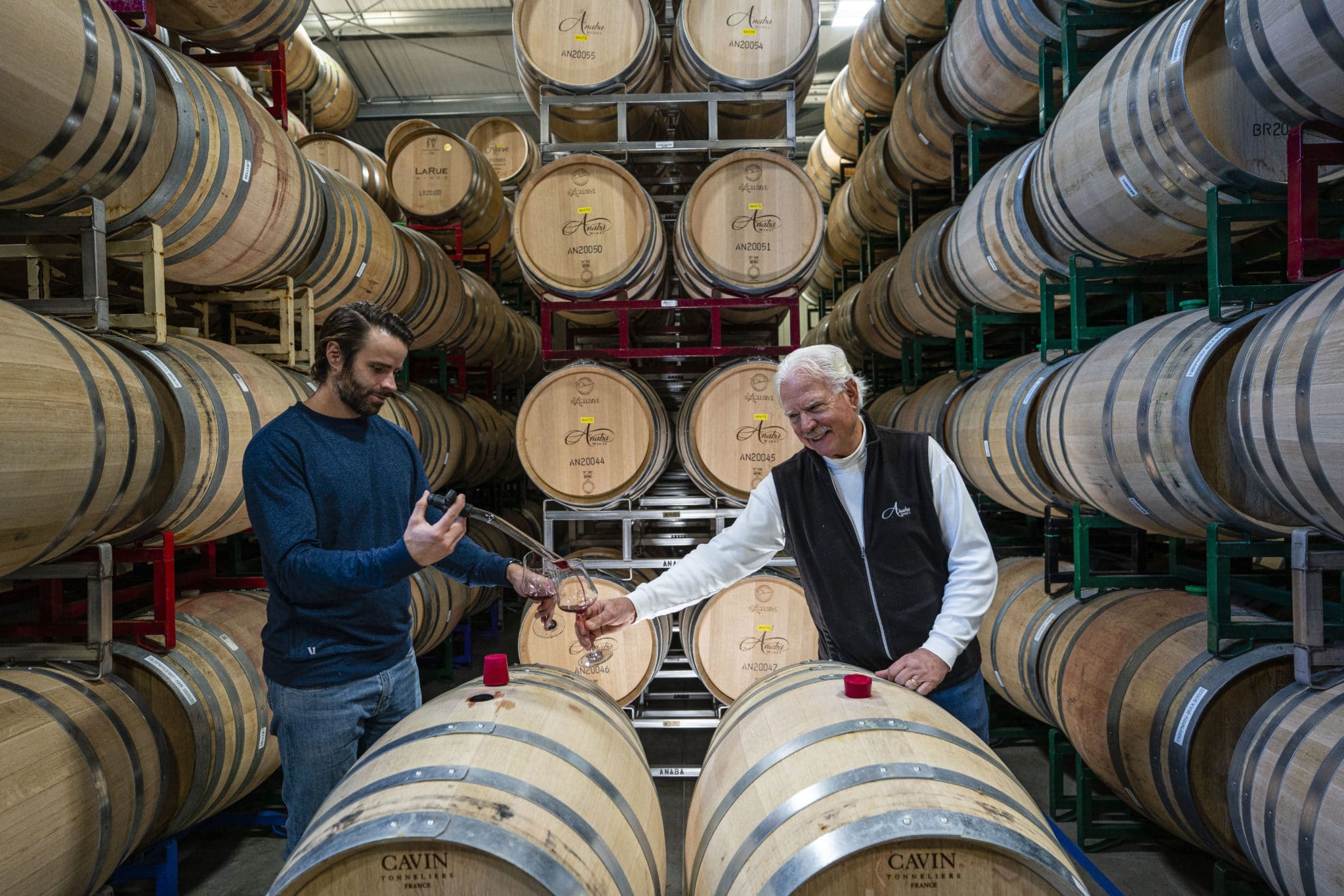 Johnny piping wine into John's glass in the winery.
