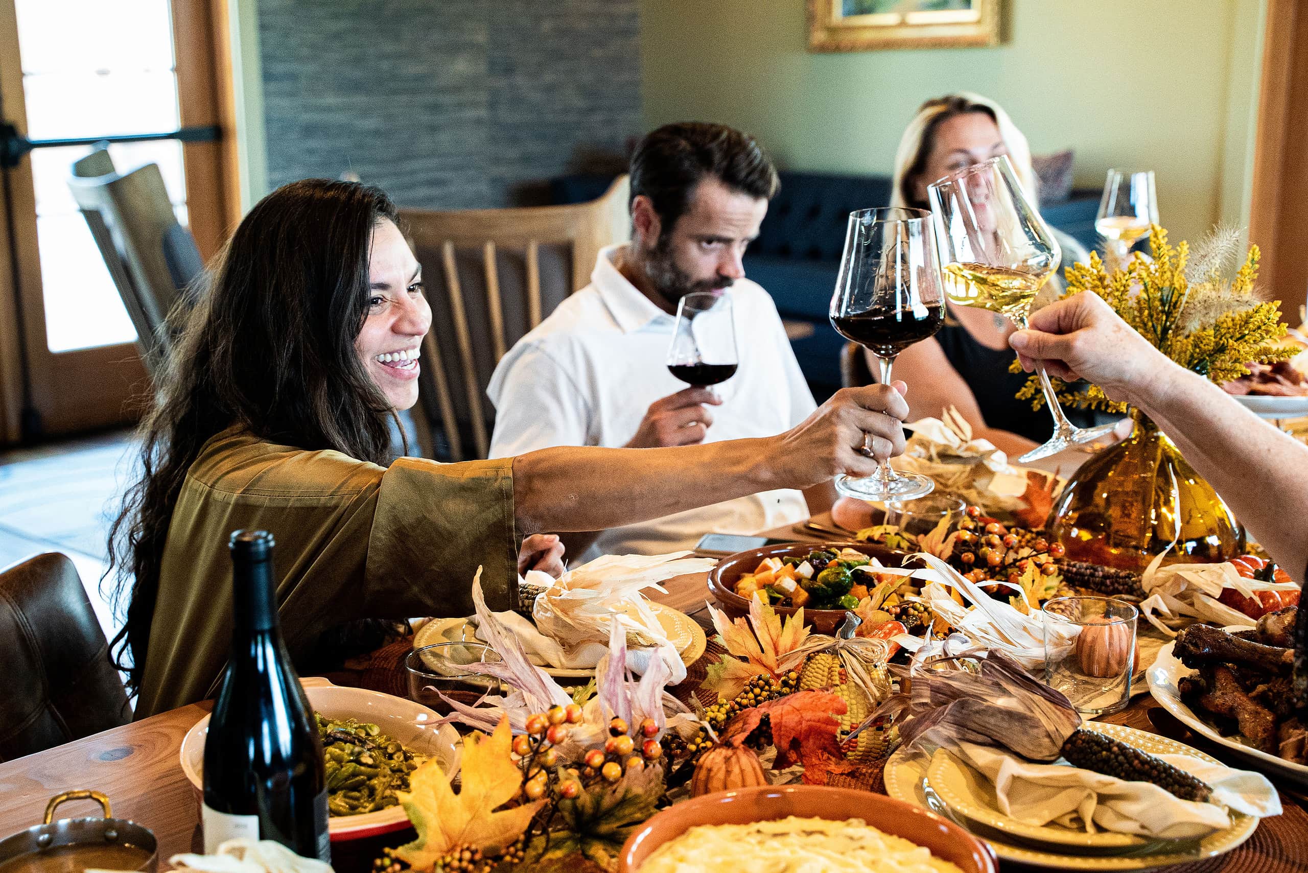 People clink glasses together over a Thanksgiving dinner table.