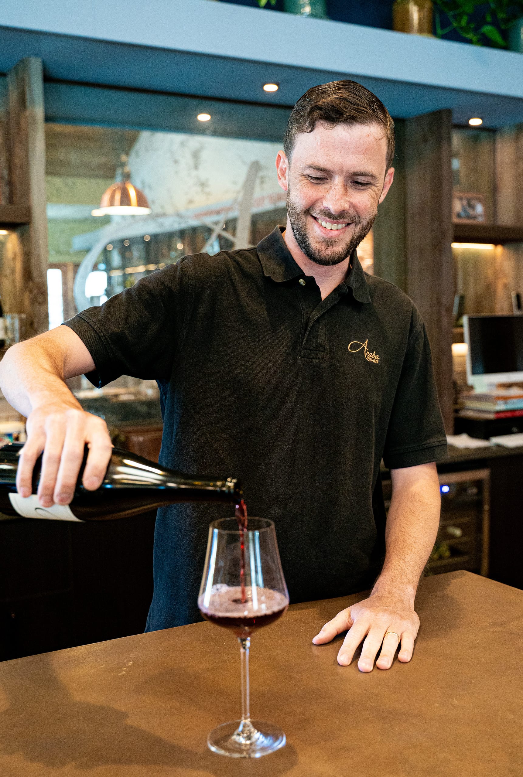 Ben, our wine club manager ours a glass of red wine.