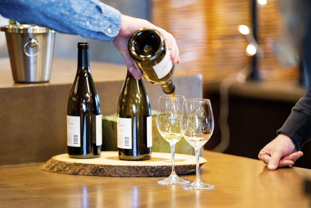 Someone pours two glasses of wine for a guest.