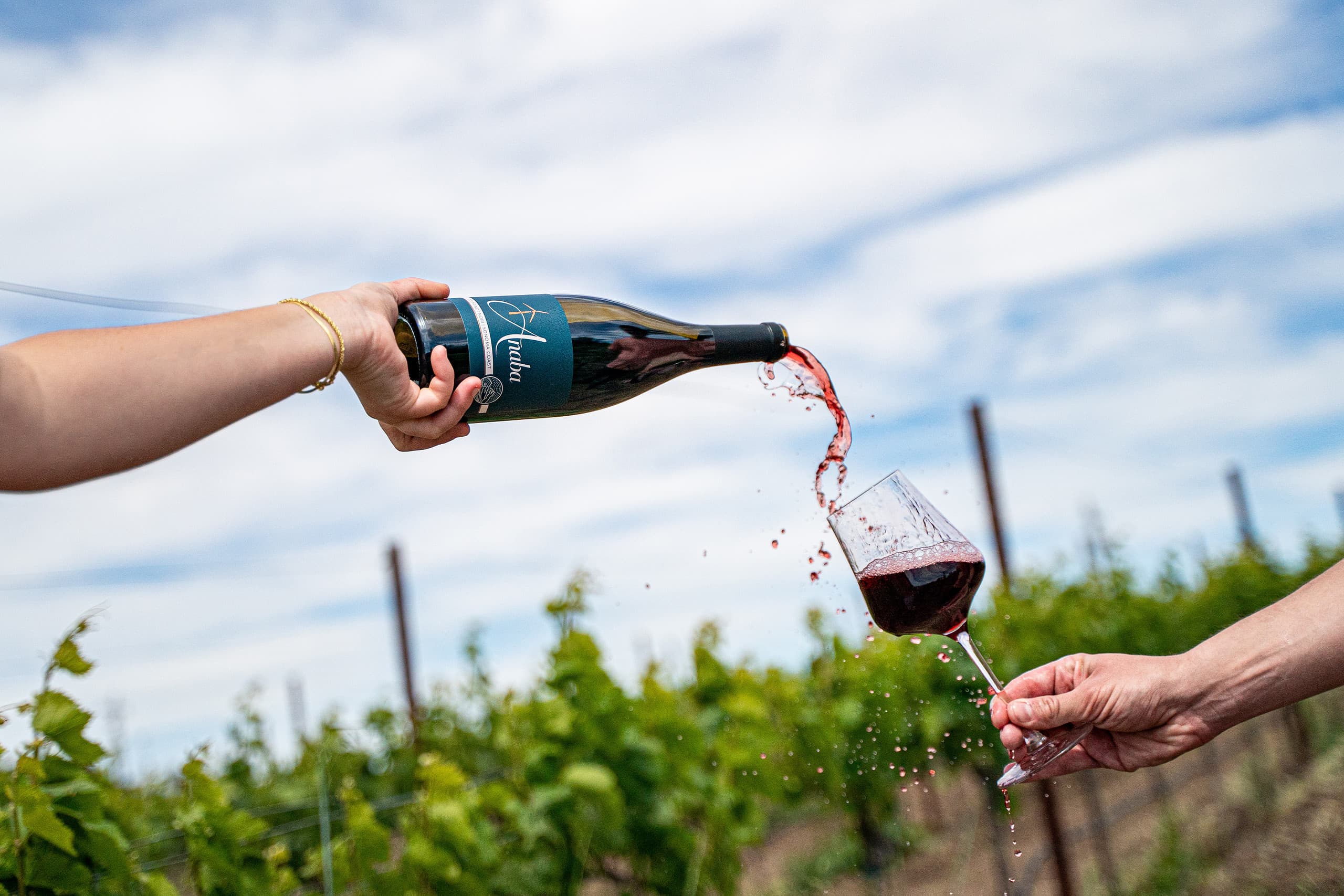 Woman's hand pouring red wine into glass, spilling some