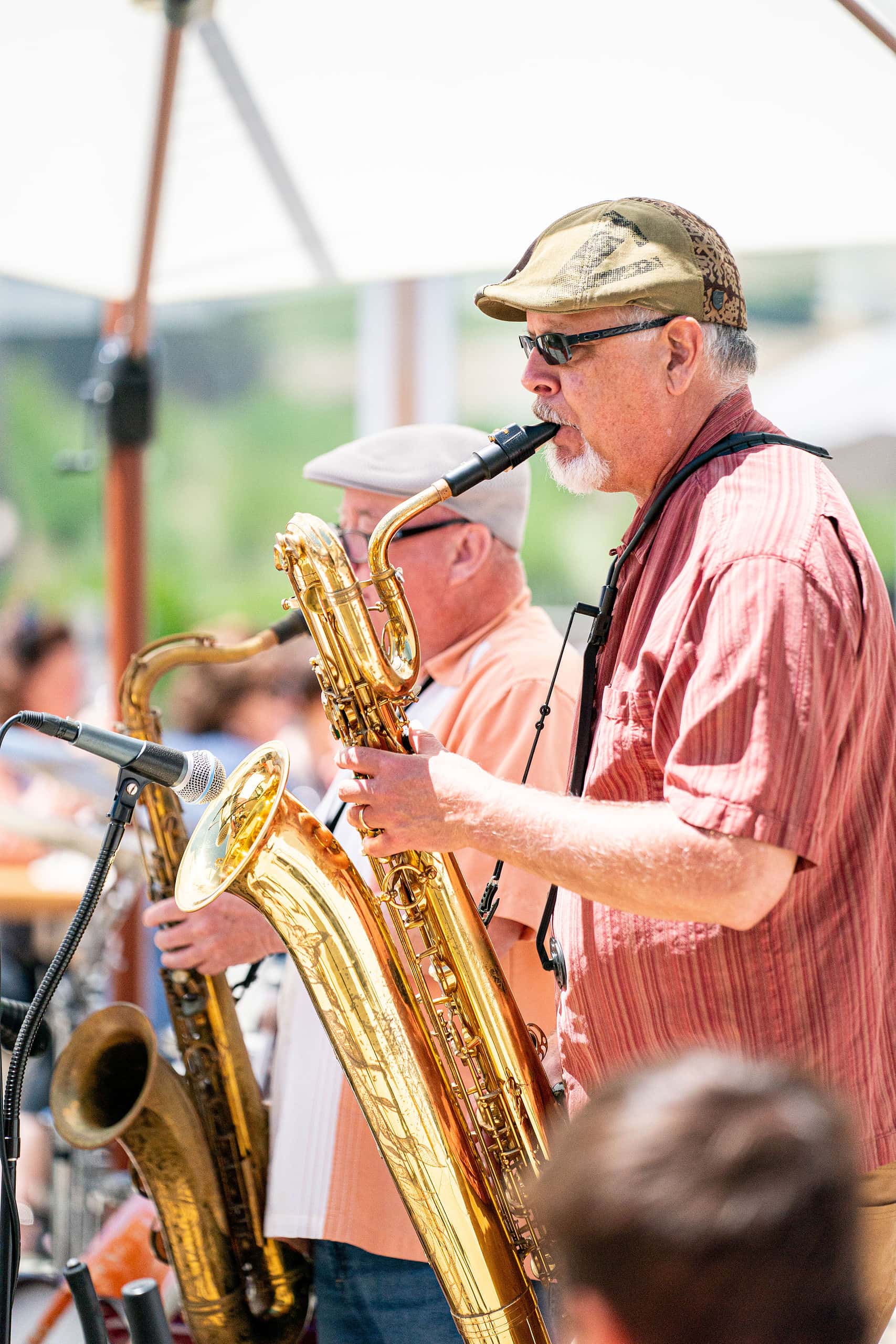 Two men playing musical instruments in the foreground, customers relaxing in the blurred background. 