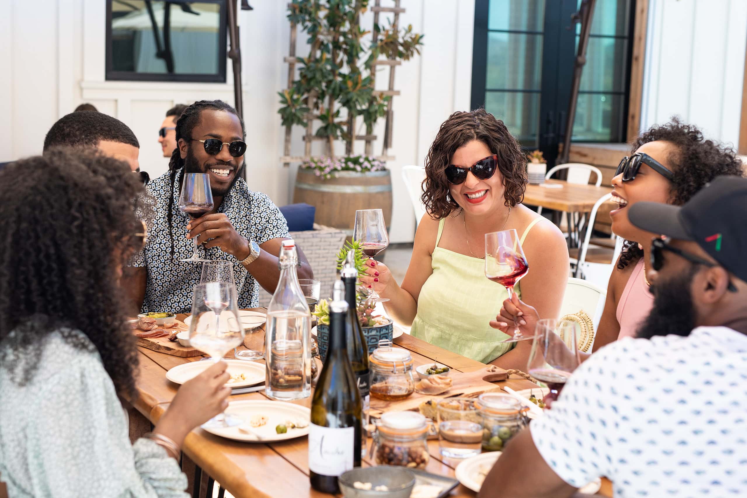 Large group of friends sitting on Anaba deck, with table full of Anaba wines and tasting room fare.