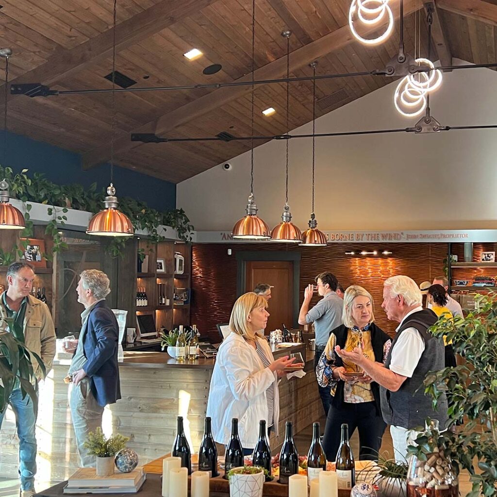 Men and women talking, whilst enjoying wine together in the Anaba Vineyard tasting room. 