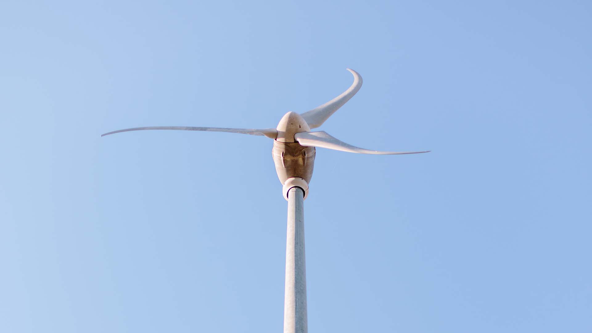 A wind turbine centred in a light blue sky.