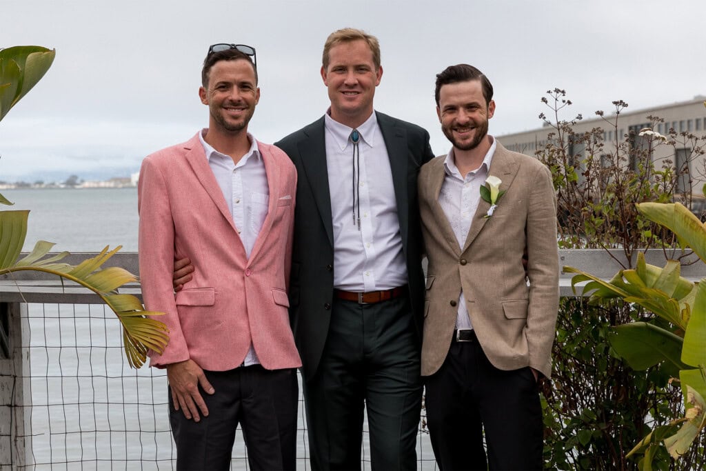 Ben, Aaron and Jack Curley dressed in suits with ocean in the background
