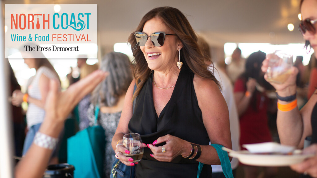 A woman with sunglasses and a drink in her hand at a wine tasting