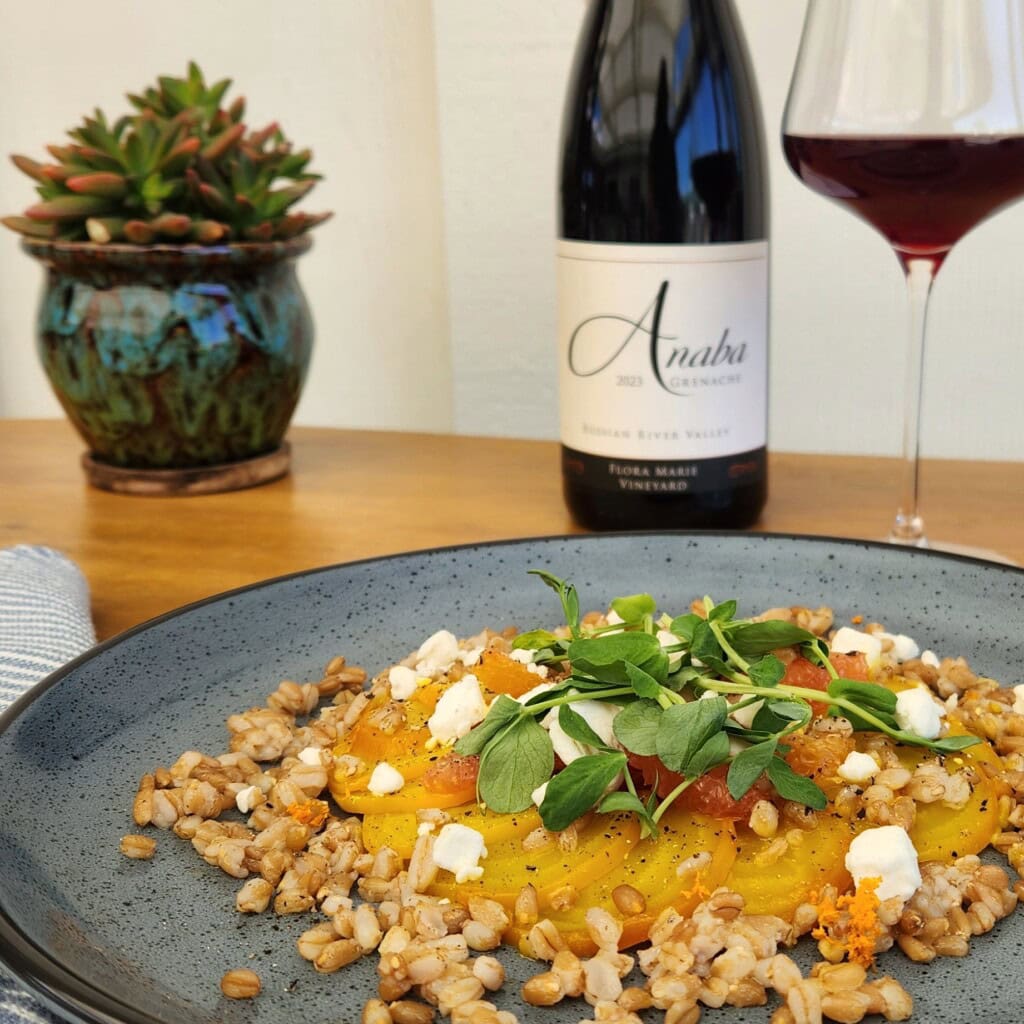 Plate of farro and beet salad on a table with a bottle and glass of Anaba Grenache wine
