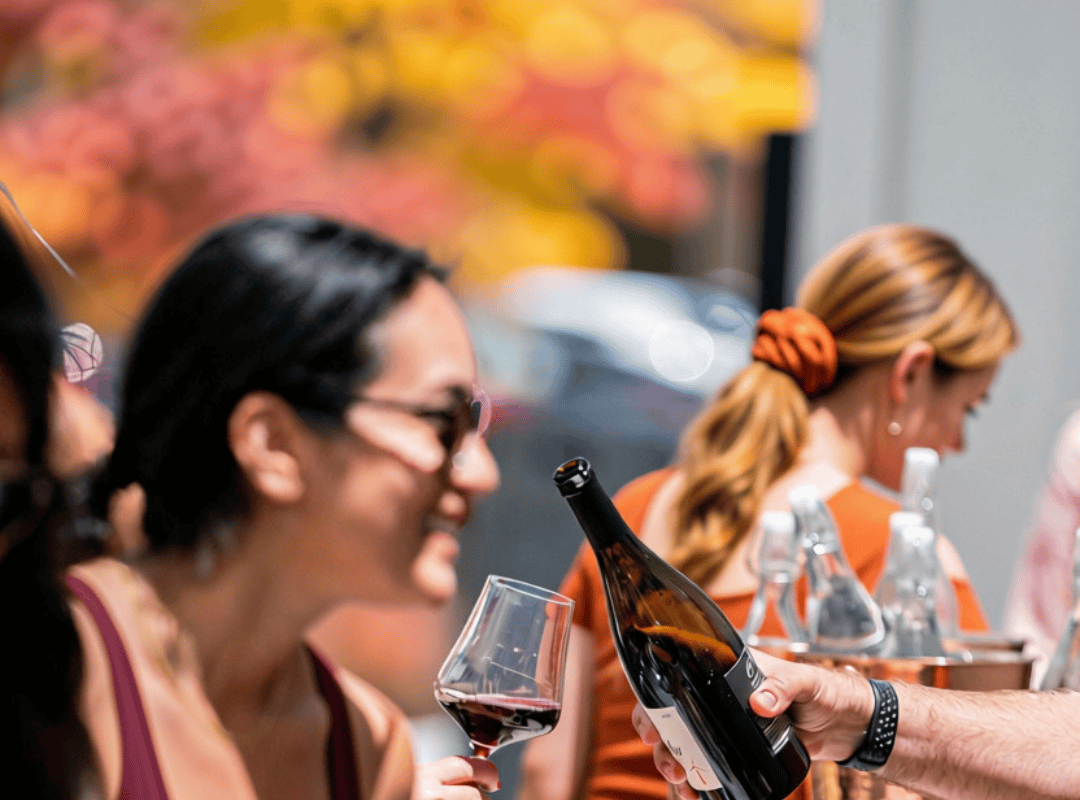 People enjoying wine tasting outdoors at Anaba Wines with autumn foliage in the background.